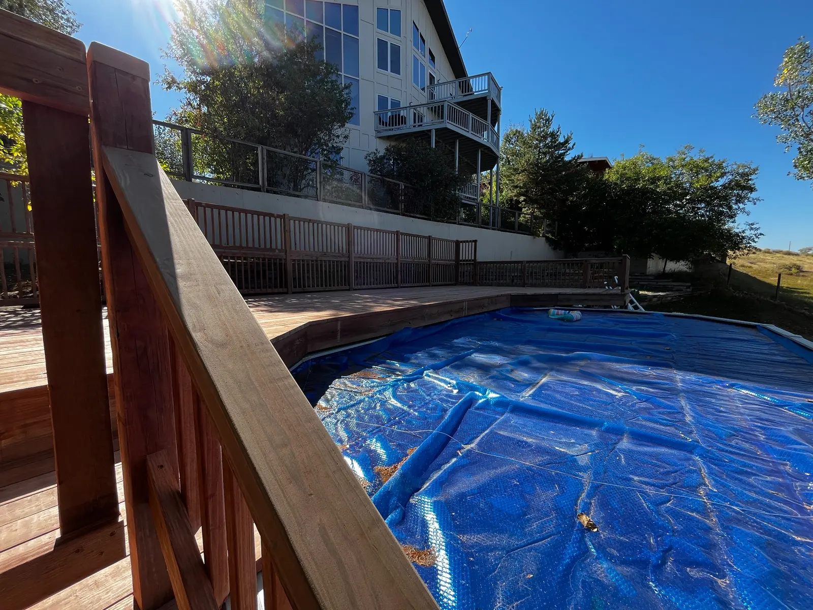 Wide view of a completed pressure-treated wood deck built around an above-ground pool at a Lakewood home