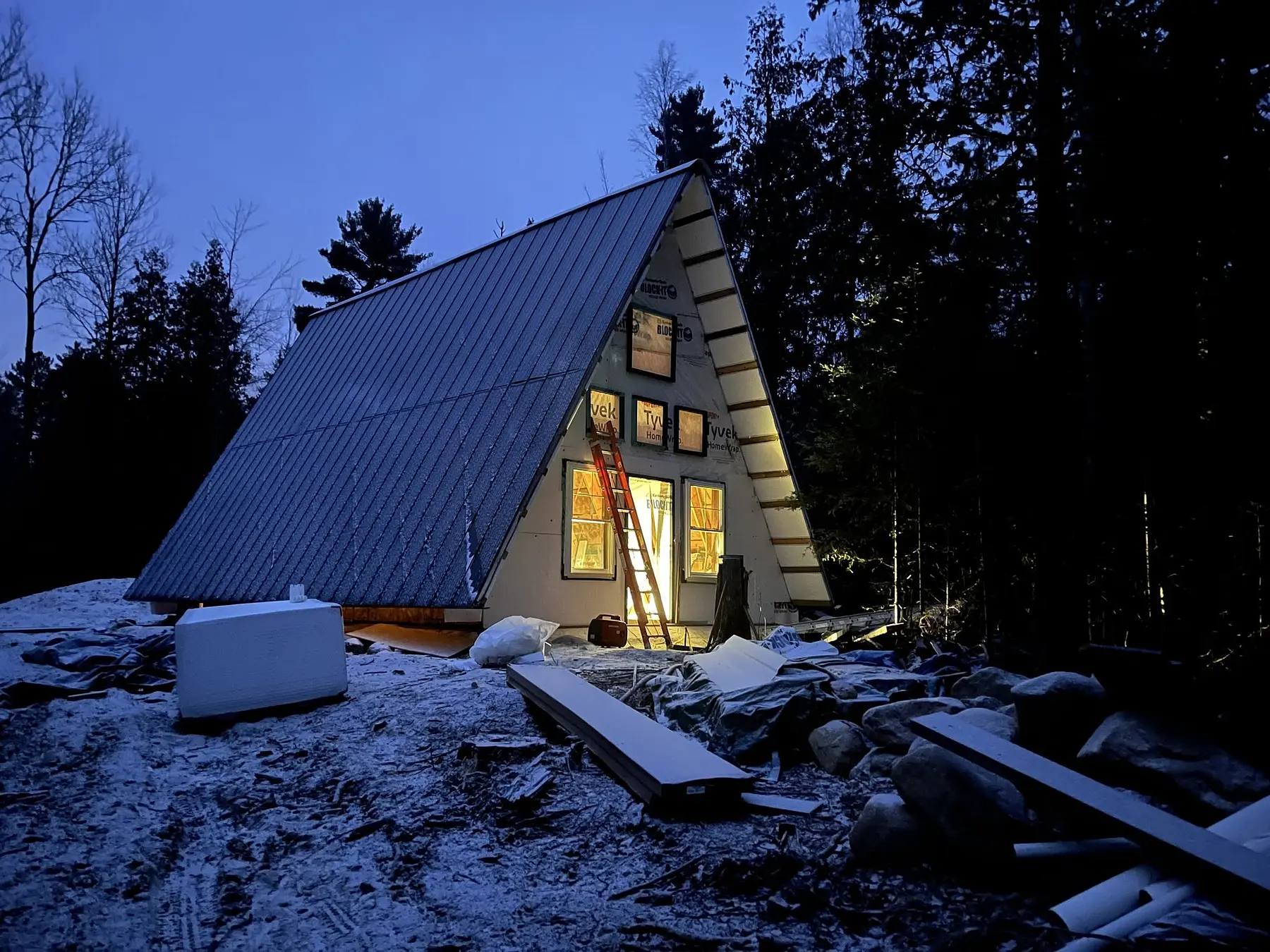 Leadville A-frame cabin under construction in winter with standing-seam metal roofing and windows installed