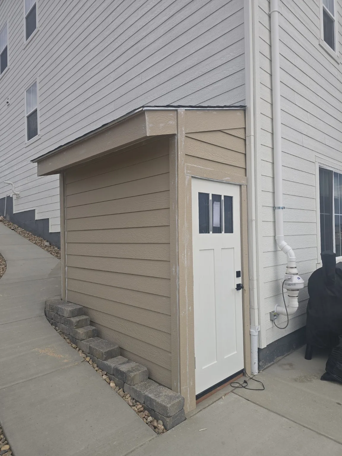 Lap siding and trim installed and primed on the Castle Rock basement entrance enclosure before final paint
