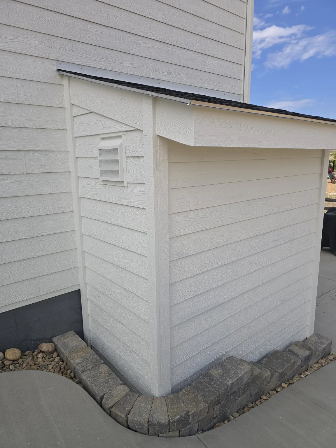 Rear corner of the Castle Rock basement entrance enclosure with wall vent and reset paver edging