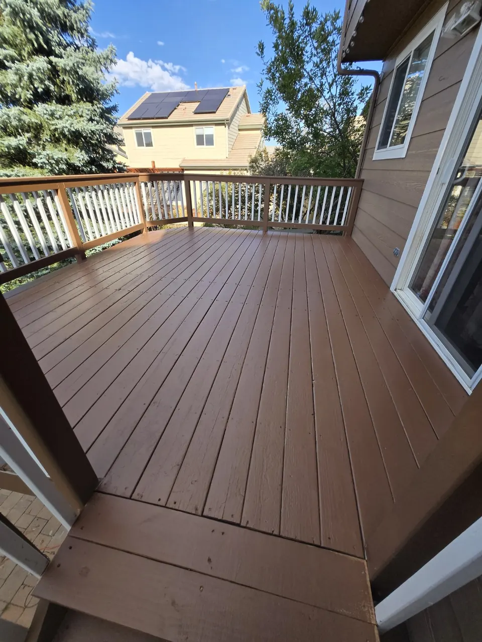 Upper deck with painted brown boards and white balusters served by the repaired stairs