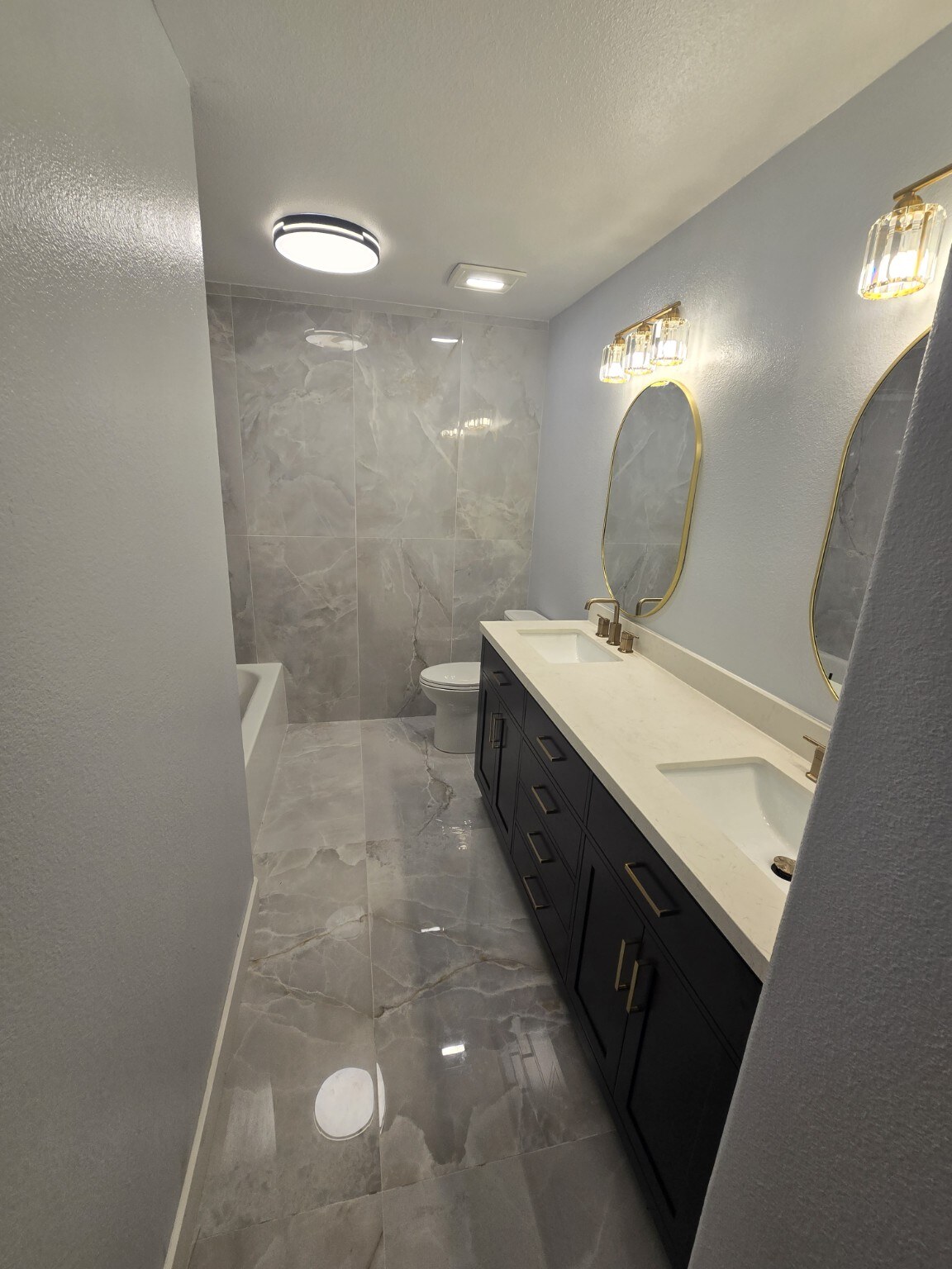 Finished Littleton bathroom renovation with black double vanity and gold mirrors