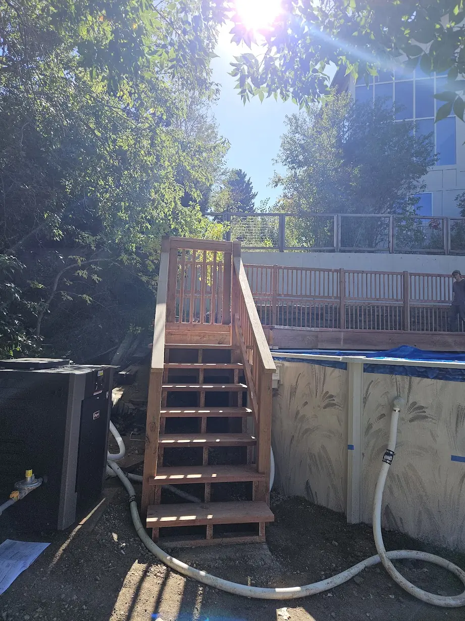 Completed pressure-treated wood staircase providing access to the elevated pool deck