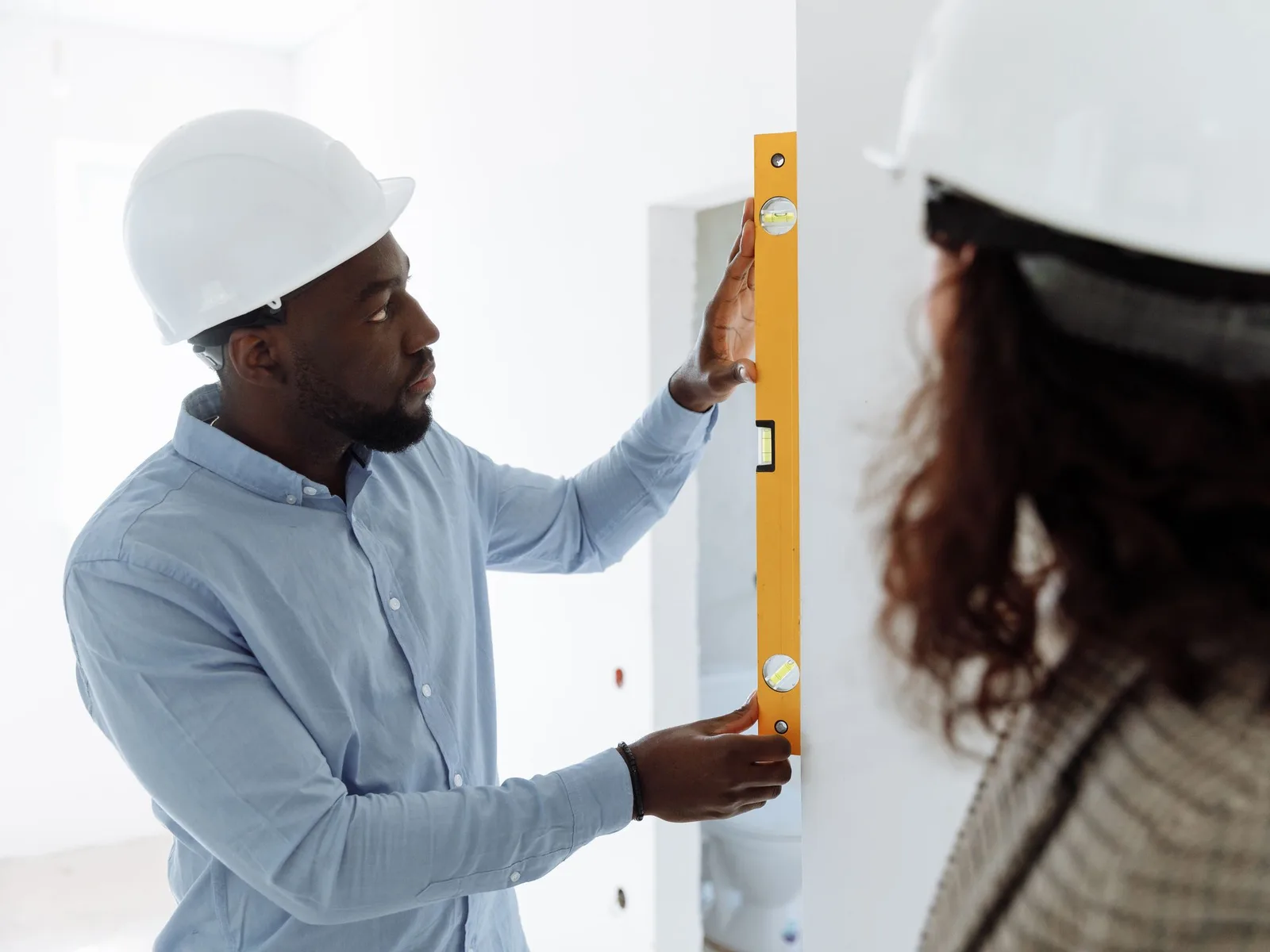 Contractor checking residential wall alignment with a spirit level.