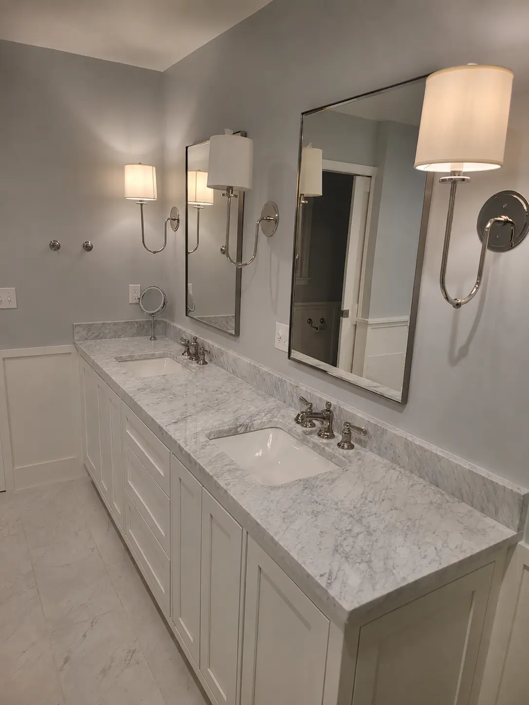 Completed double vanity with marble-look countertop, mirrors and wall-mounted lighting