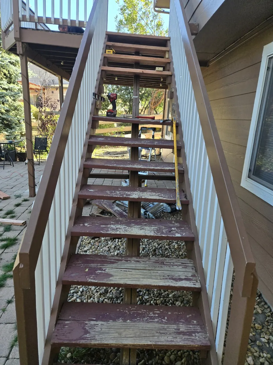 Deck stairs with a mix of old painted treads and new bare treads during repair