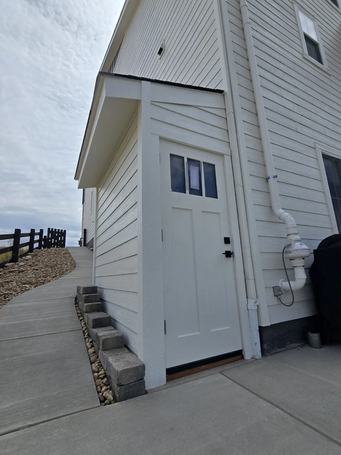 Finished basement entrance enclosure seen along the curved concrete walkway of a Castle Rock home