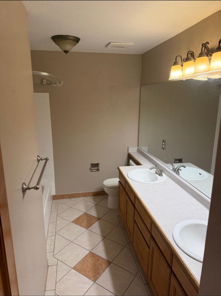 Wide view of the Littleton bathroom before renovation with patterned floor tile and old tub surround
