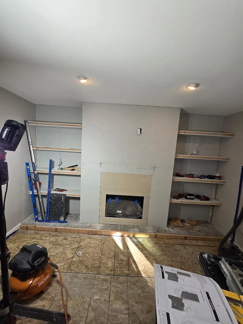 Drywall fireplace surround and symmetrical built-in shelves under construction in a Centennial living room