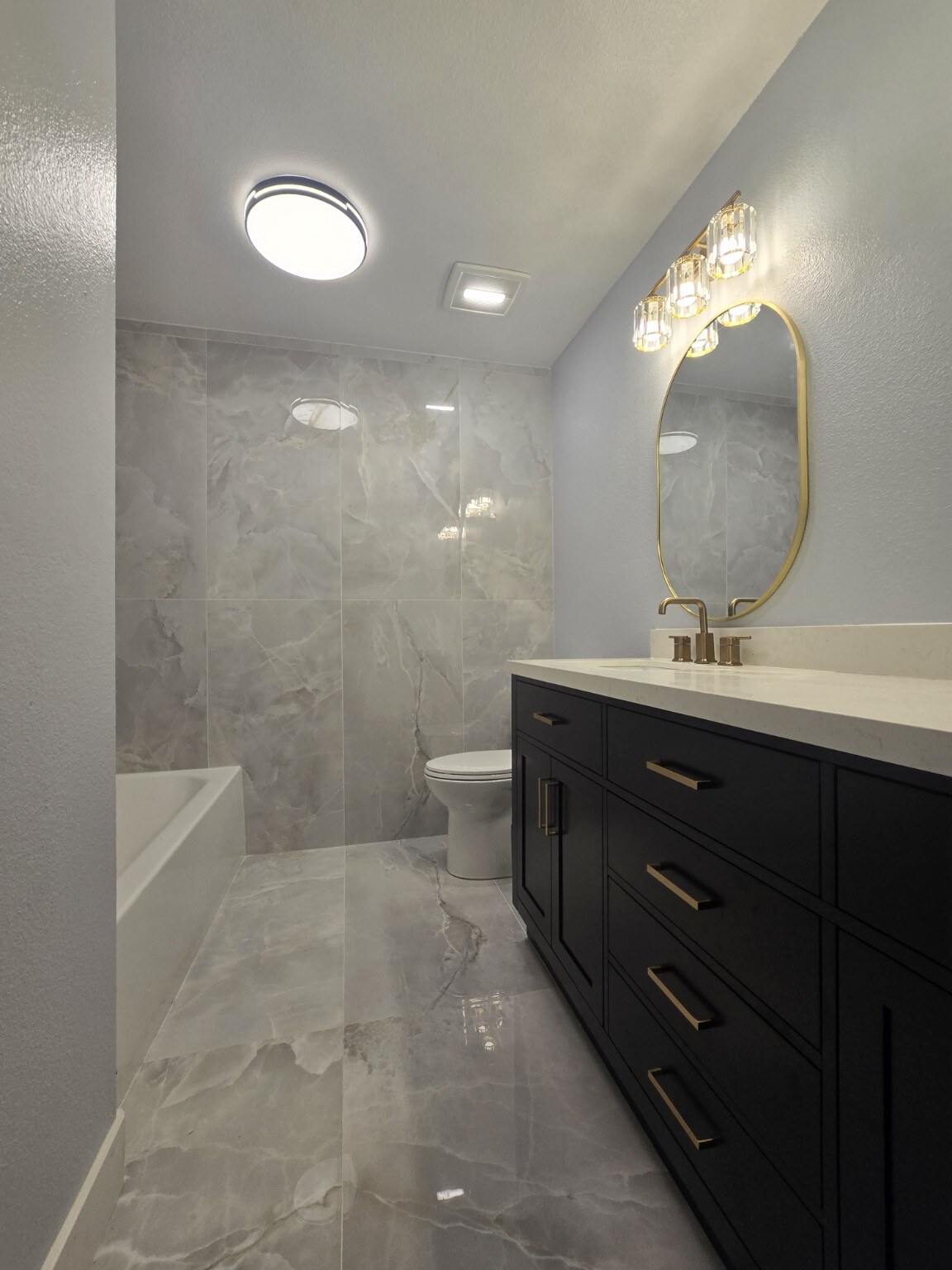 Finished Littleton bathroom view with black vanity, bathtub and full-height gray tile wall