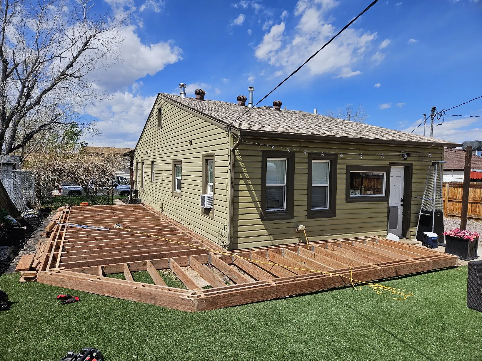 Wide view of pressure-treated framing for a wraparound deck under construction in Littleton