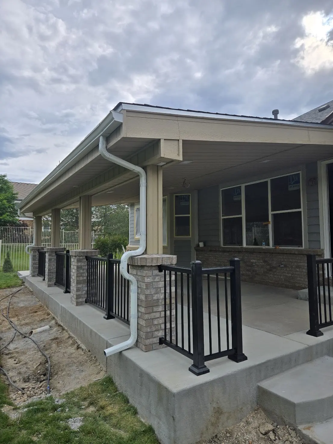 Detailed view of masonry-clad patio columns, gutters and black aluminum railings in Aurora