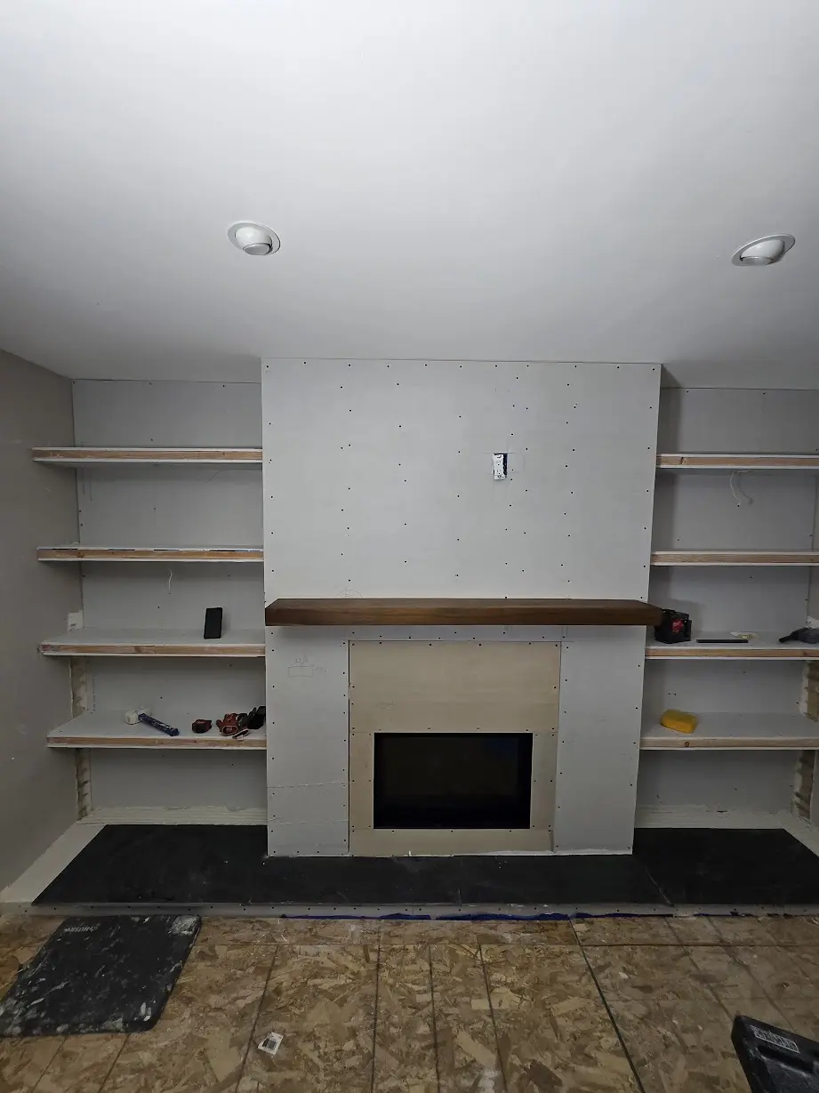 Wood mantel being installed on a gas fireplace feature wall with built-in shelves in Centennial
