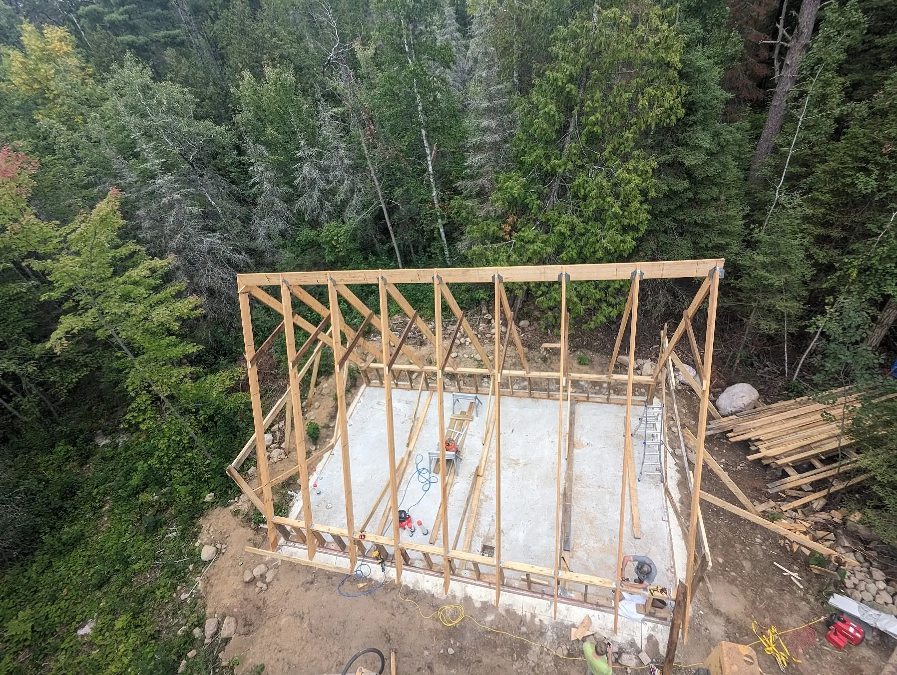 Aerial view of the ground-up A-frame structural framing on a wooded Leadville construction site