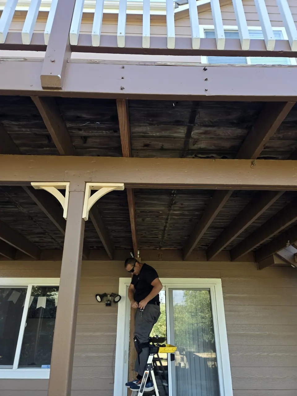 Abricos LLC worker on a ladder during framing repair under the deck