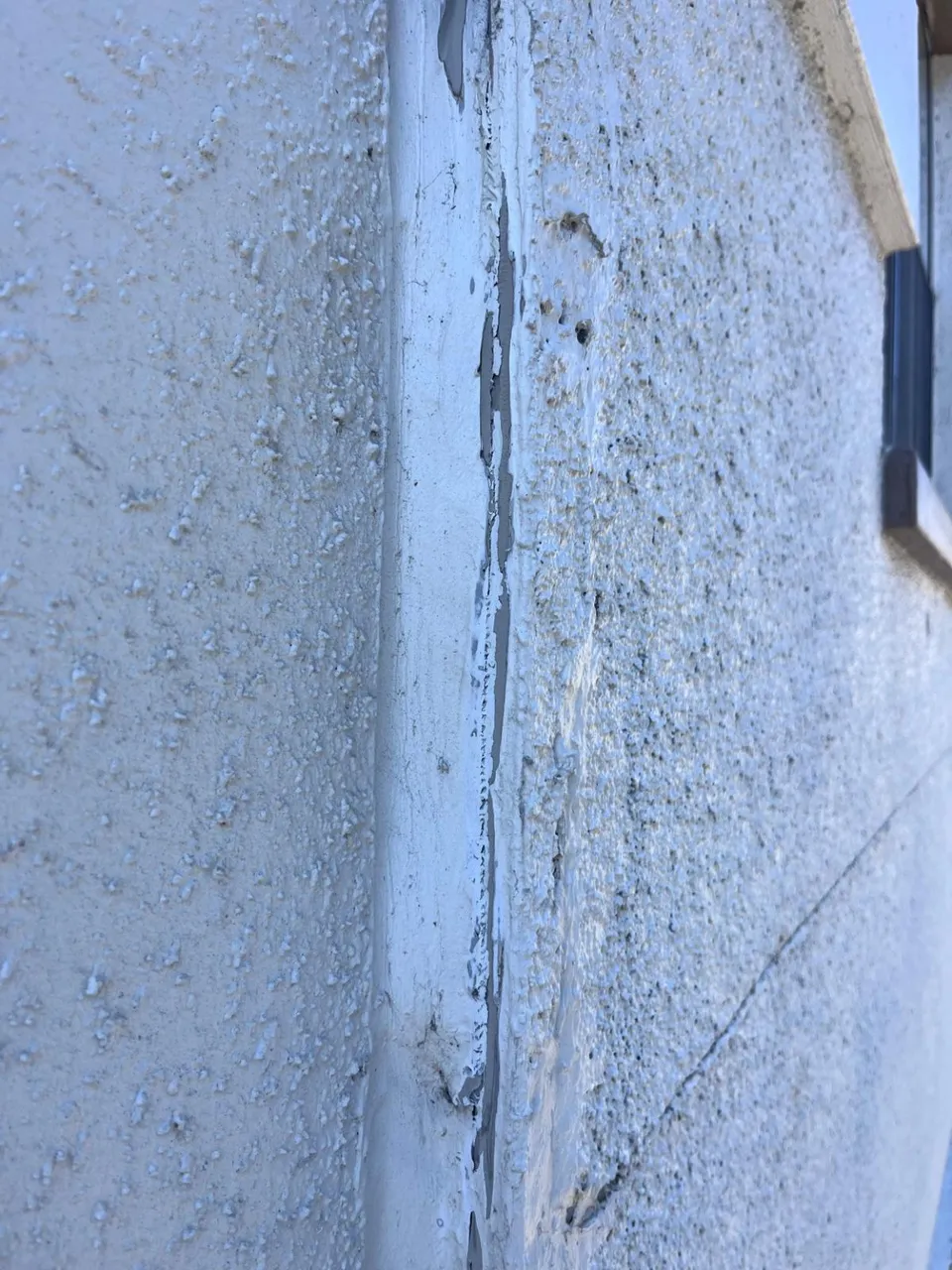 Close view of a vertical facade joint with cracked, separating old sealant before repair