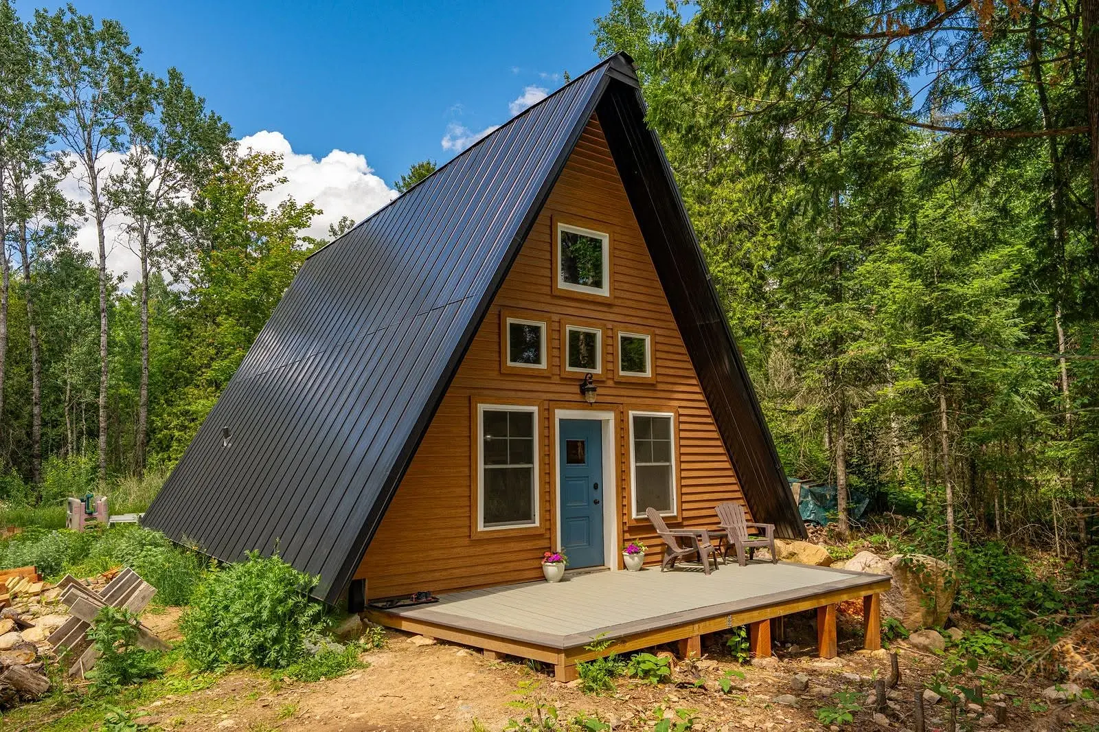 Completed A-frame cabin with standing-seam metal roof, siding and front deck in Leadville, Colorado