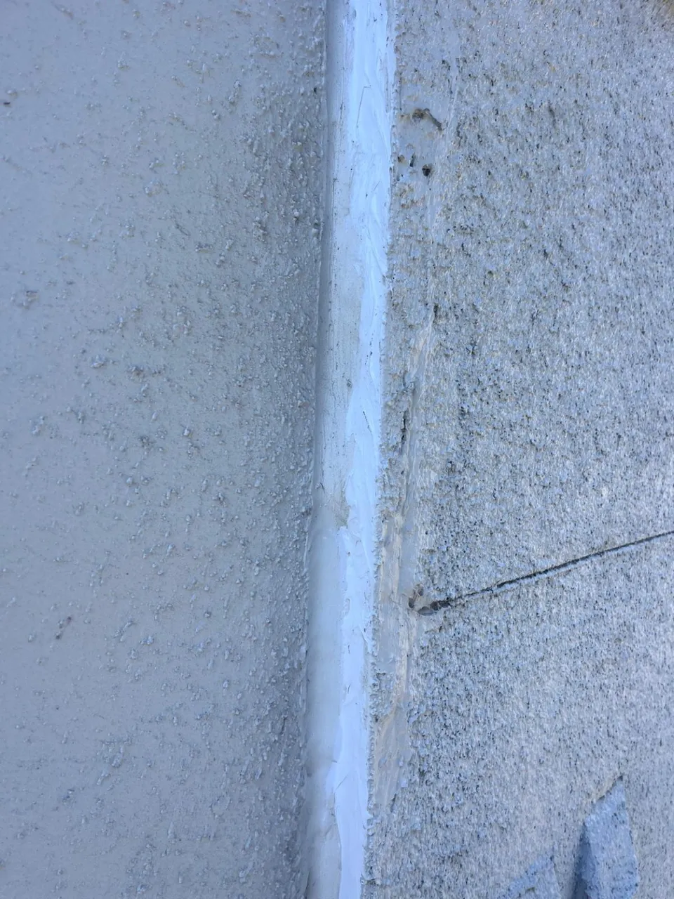 Facade joint with a continuous bead of new white sealant after repair