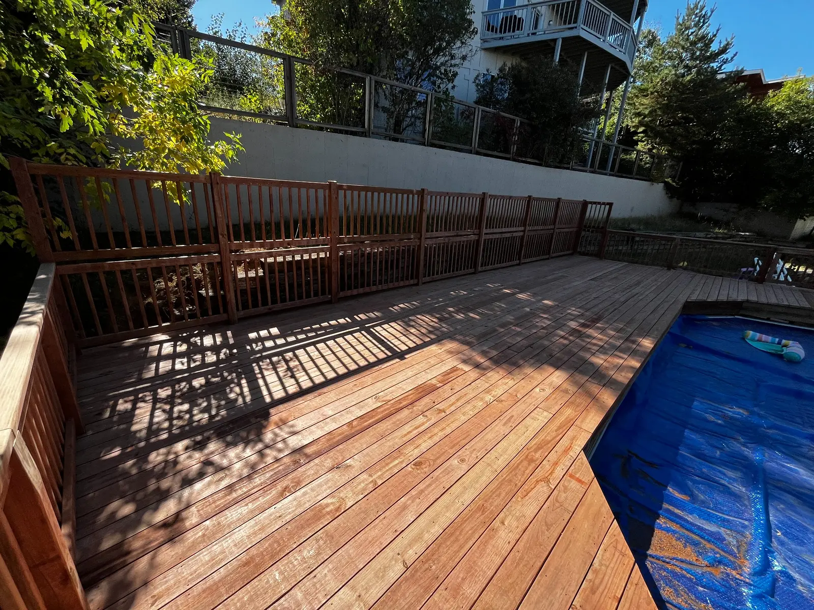 Completed pressure-treated wood decking and guardrails around a residential pool in Lakewood