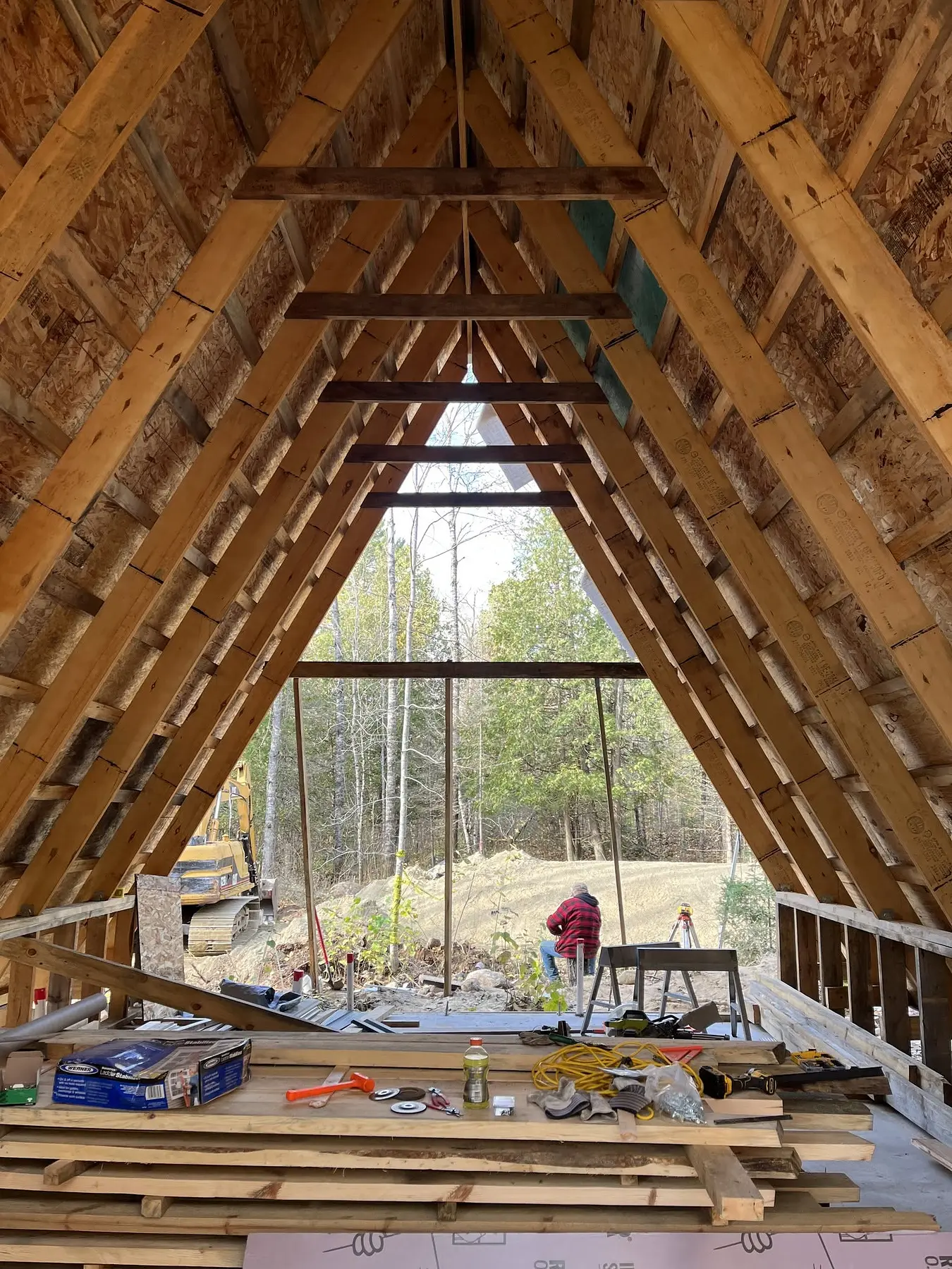 Interior view of the exposed A-frame roof structure and front window opening during construction in Leadville