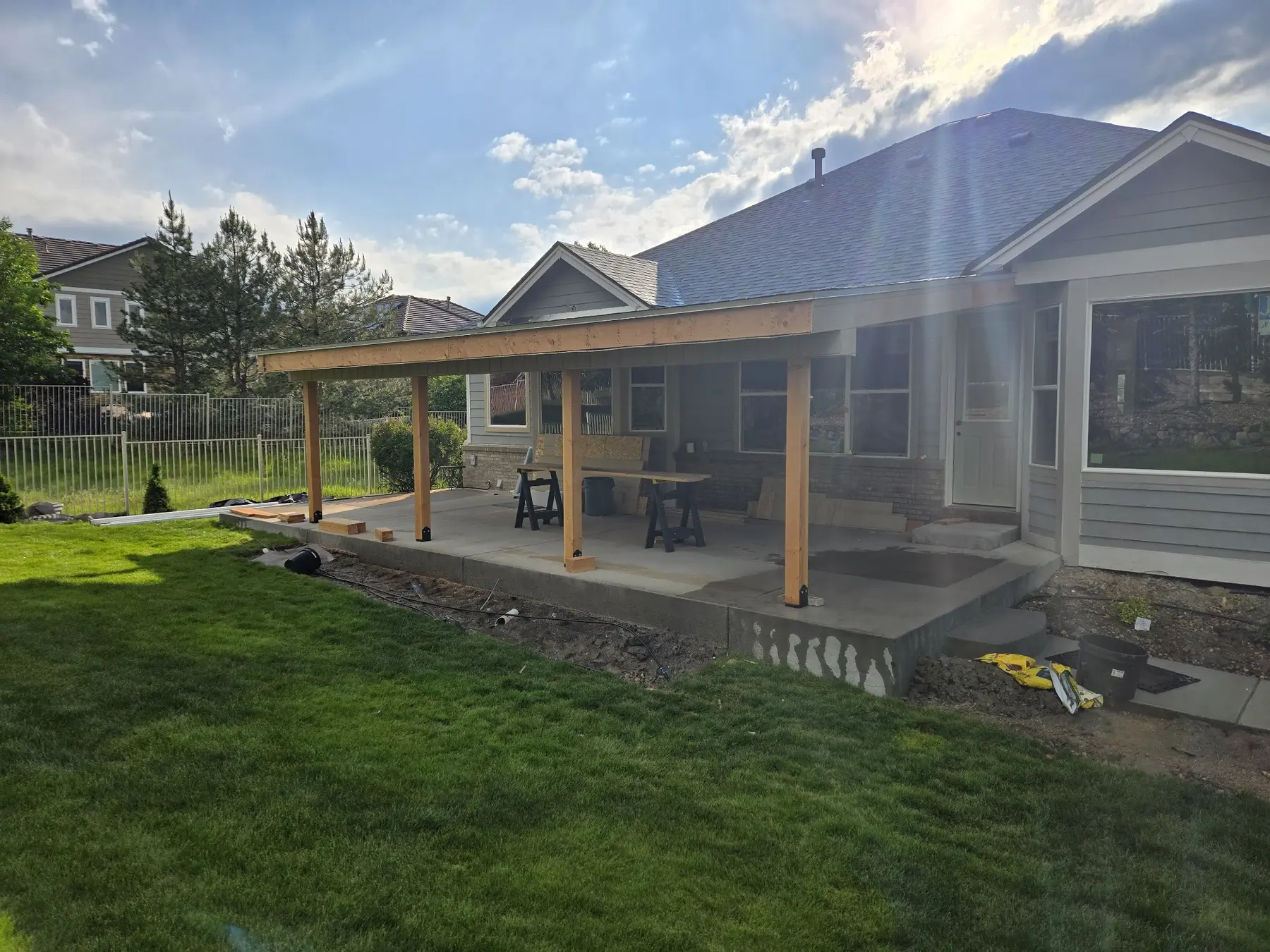 Patio roof framing under construction across the rear elevation of an Aurora house