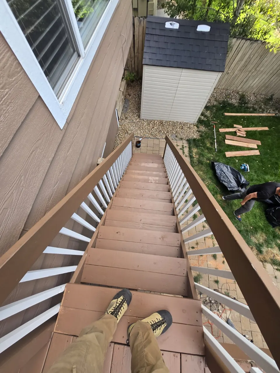 Repaired deck stairs with new treads painted brown, viewed from the top landing